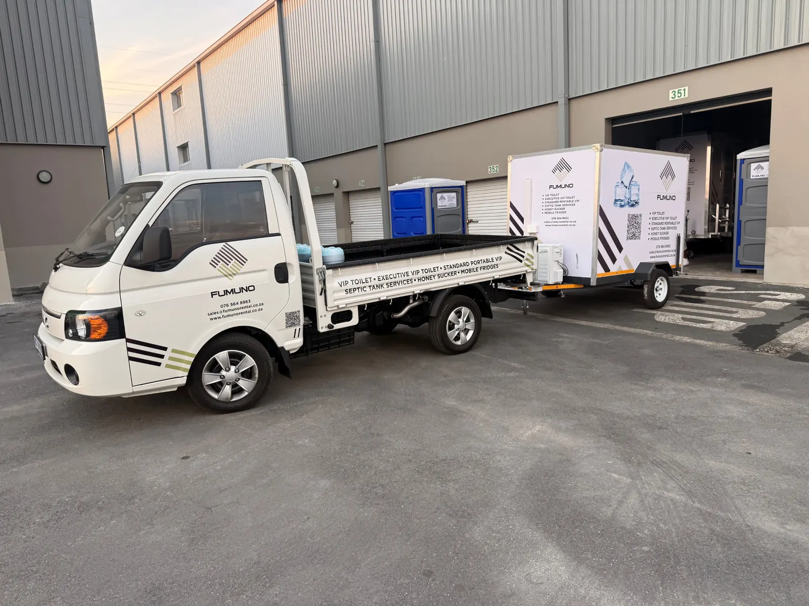 Fumuno bakkie towing a branded mobile fridge cold room trailer at the Fumuno depot with portable toilets and VIP trailers in the background