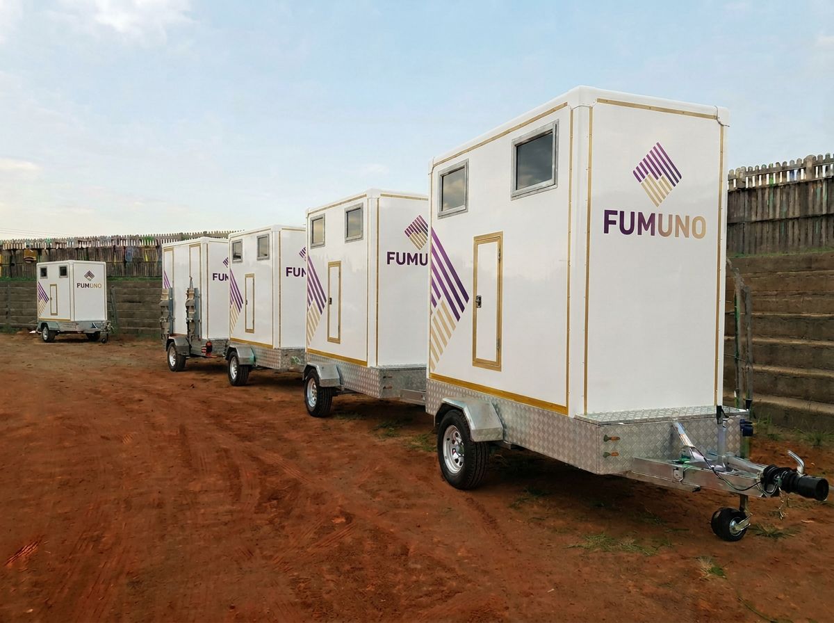 Row of Fumuno-branded standard portable toilet trailers ready for site delivery